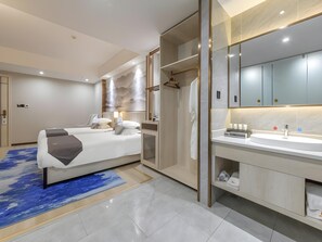 Quarto de hotel moderno com uma cama, closet espaçoso, banheiro com espelho grande e tapete azul.