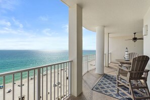 Een balkon met uitzicht op de oceaan, een tafel met stoelen en een klein model van een vuurtoren.