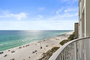 Blick auf einen Strand vom Balkon, mit Sandstrand und einem Pier im Hintergrund.