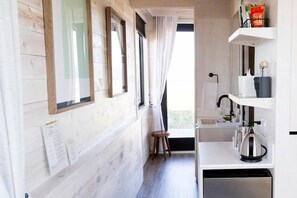 A modern kitchen with a wooden wall, a window, a sink, and a kettle. - Collective Governors Island (New York)