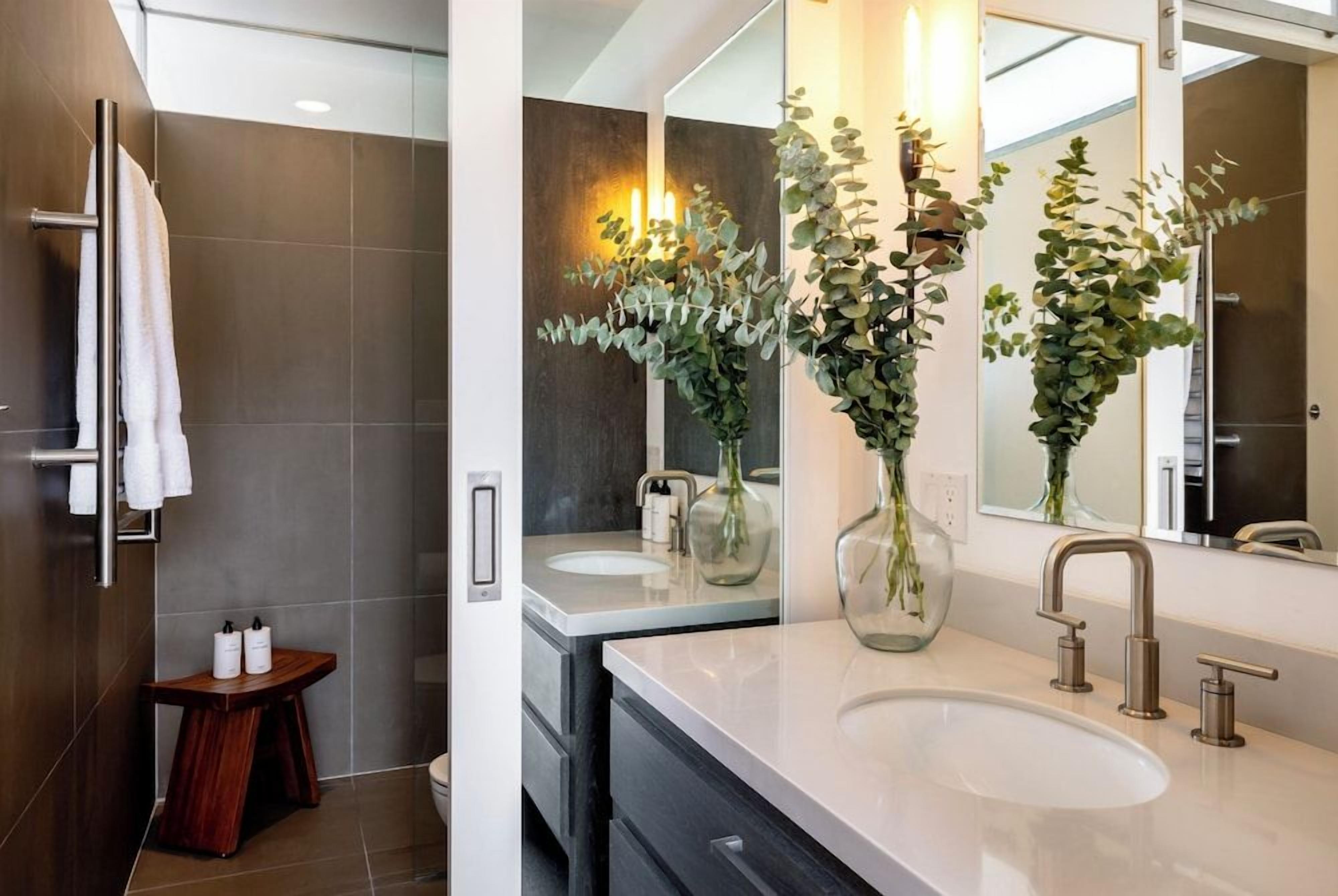 A modern bathroom with a large mirror, two sinks, and a towel rack.