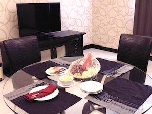 A dining area with a round table, chairs, a television, and a decorative wall.