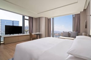 A hotel room with a large bed, a desk, a television, and a view of the cityscape. - Fuzhou Marriott Hotel Riverside (Fuzhou)
