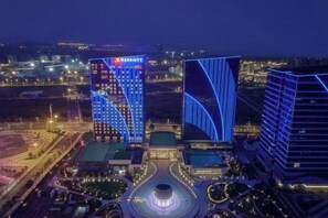 A multi-story hotel with a prominent 'Marriott' sign, surrounded by well-lit buildings and a landscaped area with a circular fountain. - Fuzhou Marriott Hotel Riverside (Fuzhou)