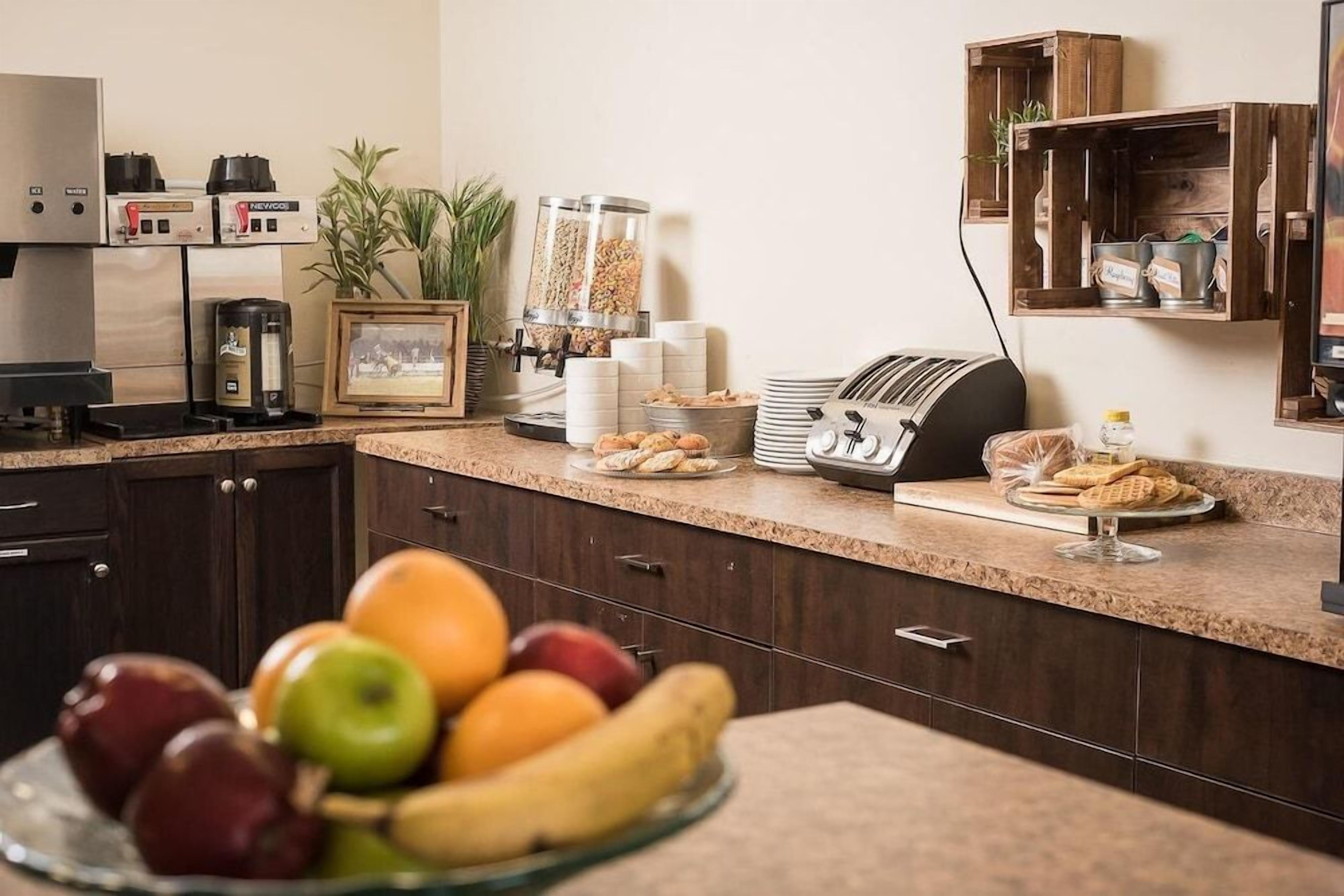 A kitchen area with a fruit bowl, a coffee machine, a toaster, and a shelf with food containers.