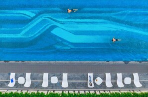 A swimming pool with two people swimming. Below the pool, there are white benches and a tiled area. - Crowne Plaza Chaozhou Riverside (Chaozhou)