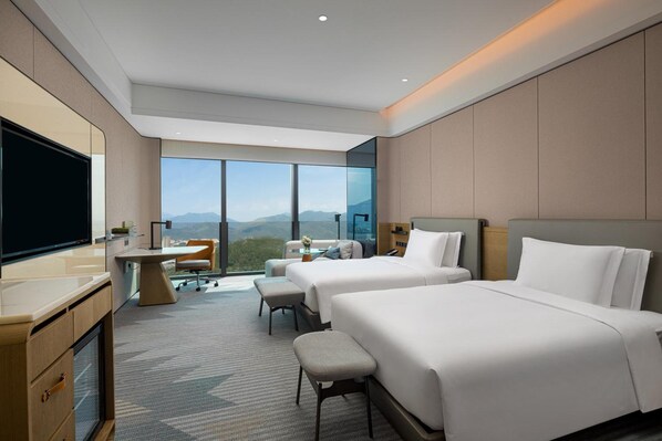 A hotel room with two beds, a desk, a TV, and a large window with a mountain view. - Crowne Plaza Chaozhou Riverside (Chaozhou)