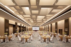 A conference room with rows of tables and chairs, a large screen at the front, and a patterned carpet. - Crowne Plaza Chaozhou Riverside (Chaozhou)