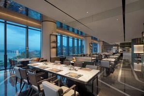 A modern restaurant with high ceilings, large windows, and a city view. - Crowne Plaza Chaozhou Riverside (Chaozhou)