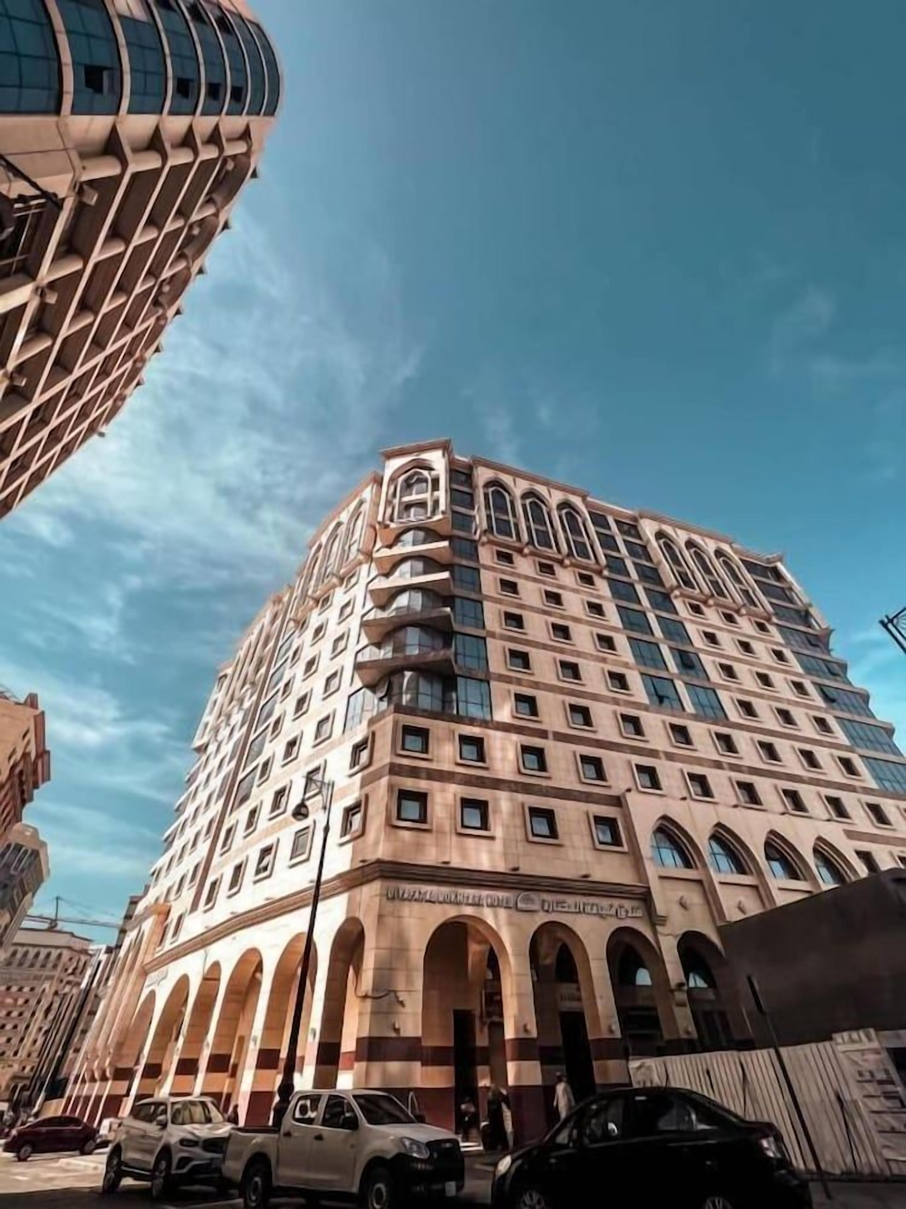 A multi-story building with a prominent corner, large windows, and a series of arches at the base.
