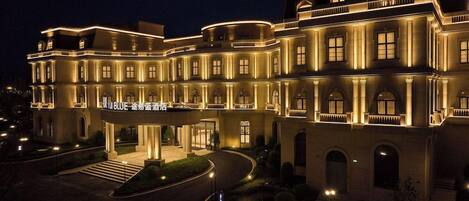 A large, multi-story hotel with a grand entrance, illuminated by warm lighting.
