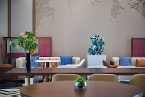 Un moderno vestíbulo de hotel con una larga mesa de recepción, asientos cómodos y decoración artística en las paredes.