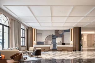 Un hall de hotel con mostrador de recepción, zona de estar y grandes ventanales.