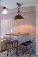 Un comedor con una mesa, cuatro sillas, una lámpara colgante y una pared con textura.