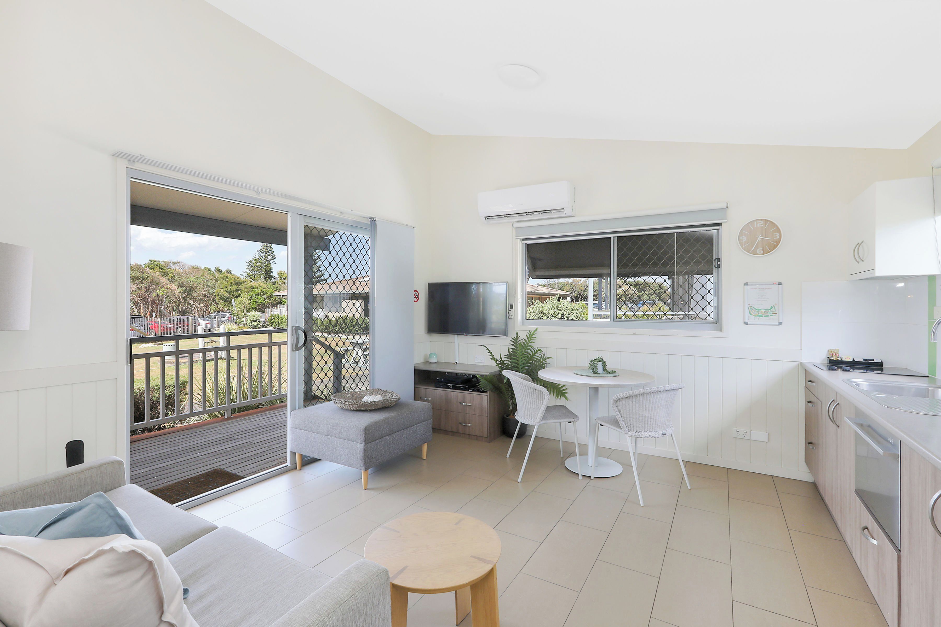 A modern apartment with a balcony, a kitchenette, a dining area, and a living space.