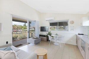 Un apartamento moderno con balcón, kitchenette, comedor y sala de estar.