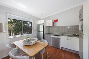 Una cocina moderna con armarios blancos, un refrigerador de acero inoxidable, un lavavajillas y una ventana con vistas a zonas verdes.
