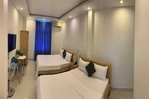 Une chambre d’hôtel avec deux lits, un bureau, une chaise et un téléviseur.