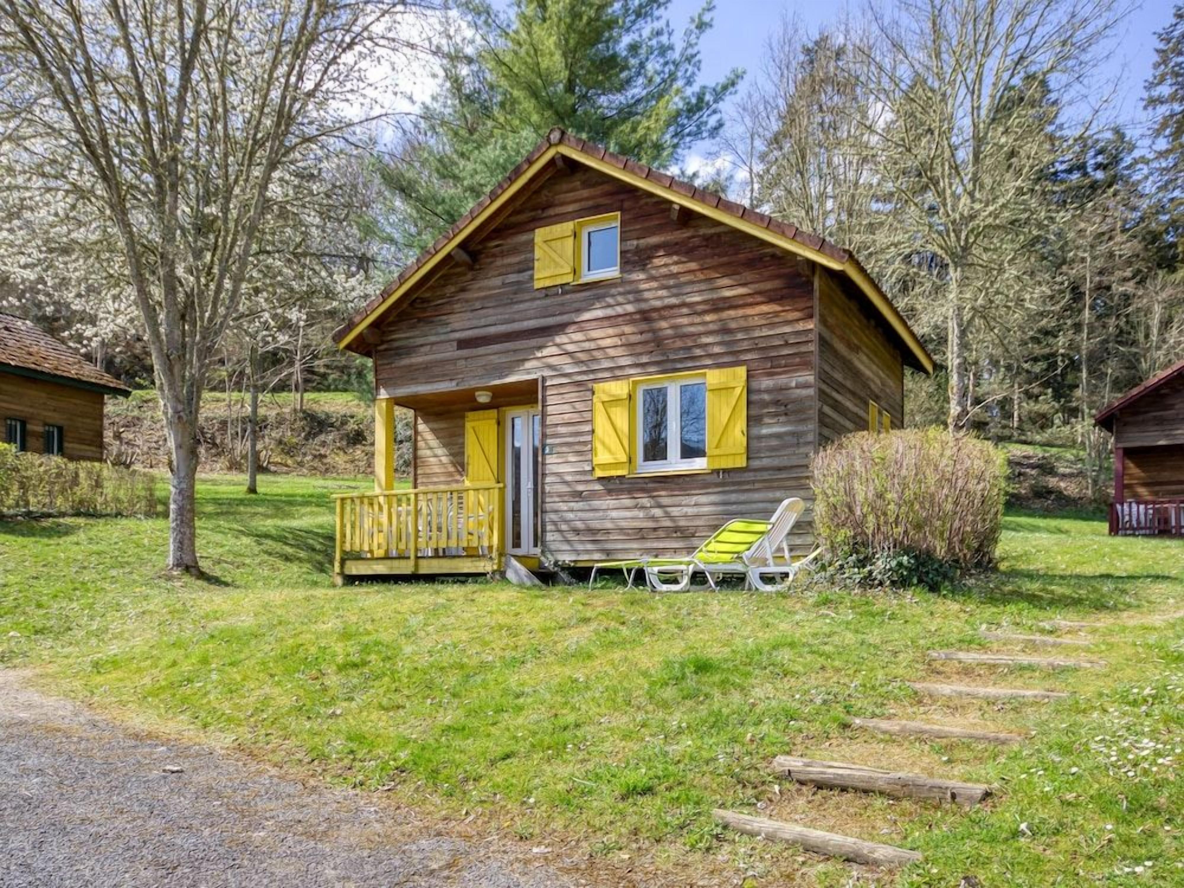 A wooden cabin with a porch and two chairs outside.