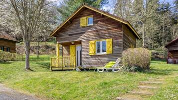 A wooden cabin with a porch and two chairs outside.