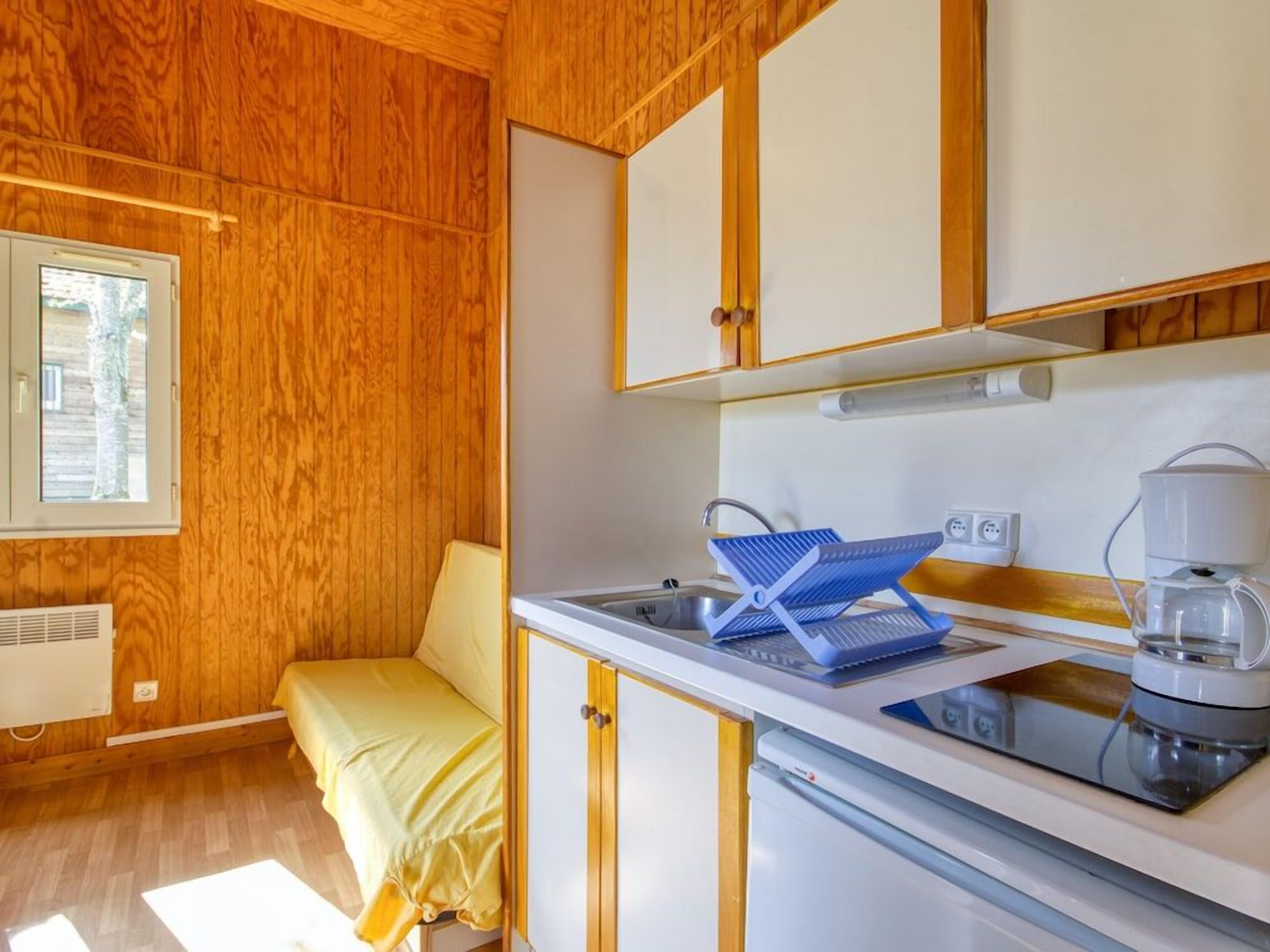 A compact kitchen with a sink, a coffee maker, and a small dining area with a yellow table and bench.
