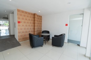 A reception area with a patterned wall, two black chairs, a small round table, and a door with a red sign. - Swing & Pillows AT Klebang, Melaka (Malacca City)