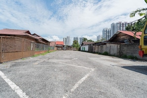A paved street with buildings on both sides, a fenced area, and a clear sky.