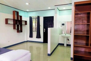 A hotel room with a bed, a bathroom with a sink, and a wardrobe.