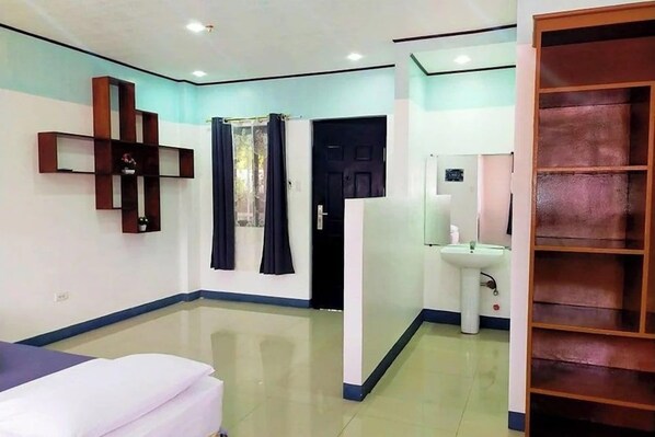 A hotel room with a bed, a bathroom with a sink, and a wardrobe.