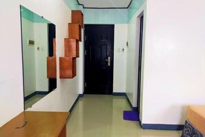 A hallway with a mirrored wall, a wooden bench, and a door at the end.