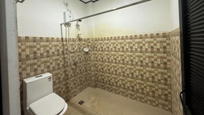 Een kleine douchecel met betegelde wanden en een toilet.