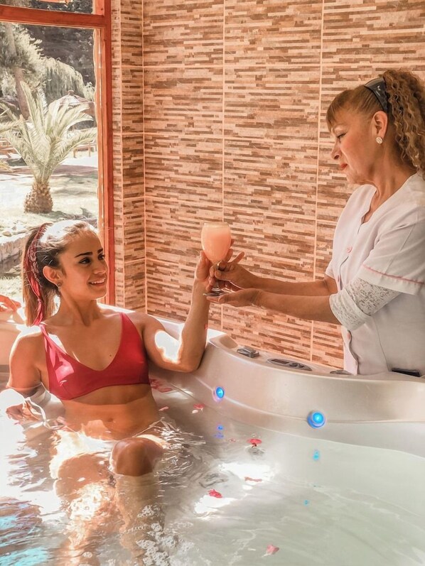 Une personne dans une baignoire, avec un mur en bois et une fenêtre en arrière-plan.
