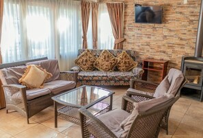 Una sala de estar con sofá, sillas, una mesa de centro y chimenea.
