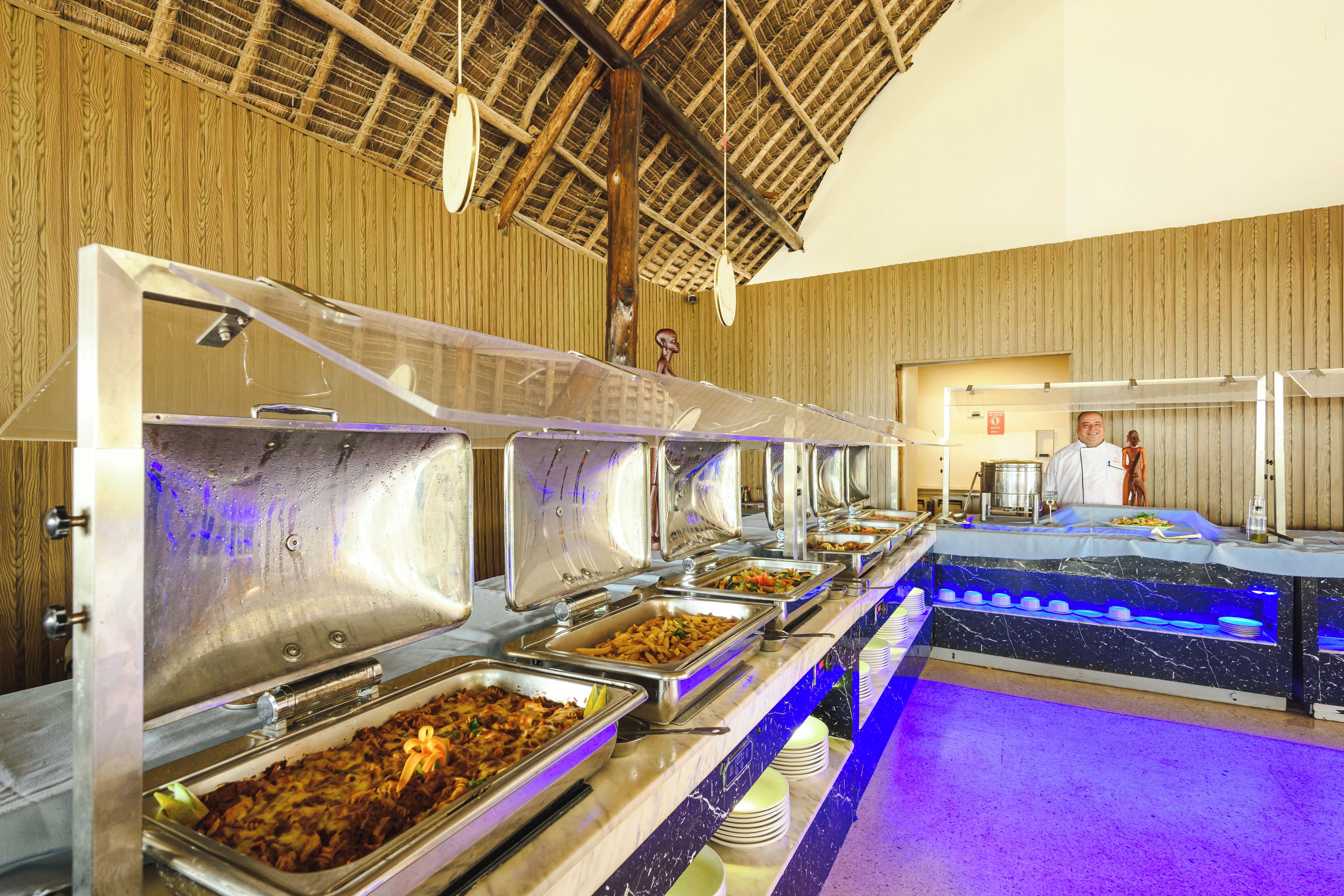 A buffet setup with multiple food service stations, a chef in uniform, and a wooden interior.