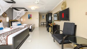 Una habitación de hotel con cama, mesita de noche, silla, televisión y ventilador de techo.