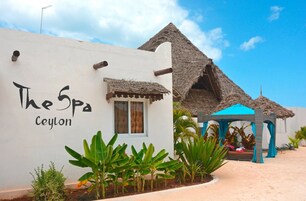 Un edificio con un letrero que dice "The Spa Ceylon" y una estructura con techo de paja.