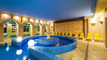 Una piscina interior con múltiples carriles, sillas de descanso amarillas y una pared decorativa.