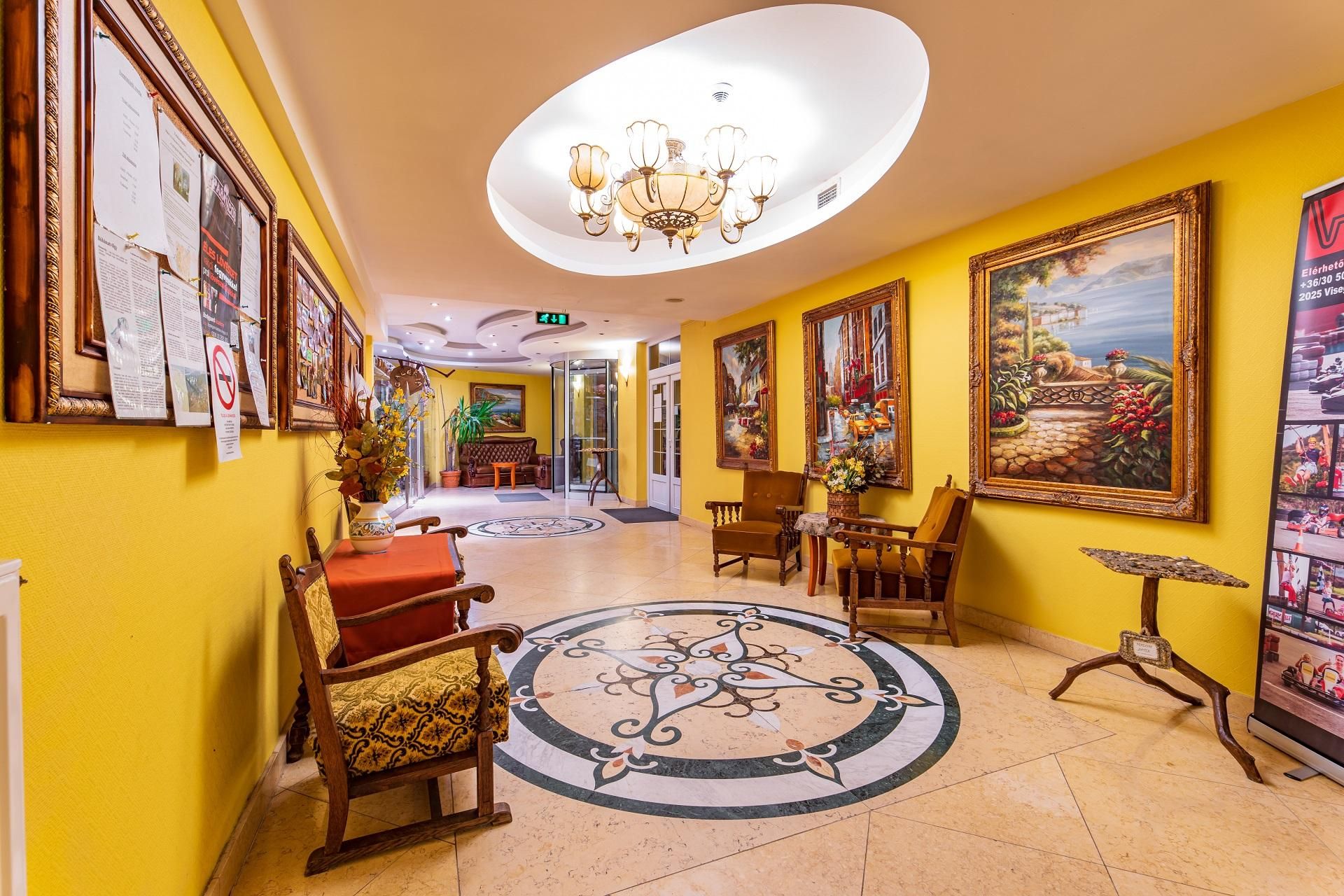 Un hall de hotel con una araña central, un suelo circular con diseños y varias obras de arte enmarcadas en las paredes.