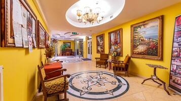 Un hall de hotel con una araña central, un suelo circular con diseños y varias obras de arte enmarcadas en las paredes.