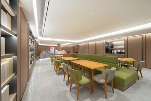Et moderne bibliotek med bogreoler, borde og grønne siddeområder.