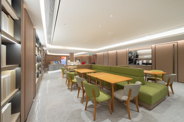 Una biblioteca moderna amb prestatges, taules i zones d'seure amb seients verds.