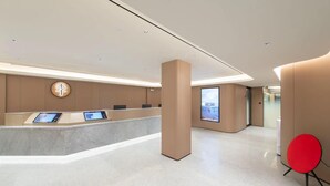 Un área de recepción moderna con un mostrador curvo, quioscos digitales y una gran pantalla digital.