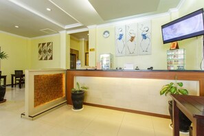 A hotel reception area with a reception desk, a television, and artwork on the wall. - Aiqo Hotel (Balikpapan)