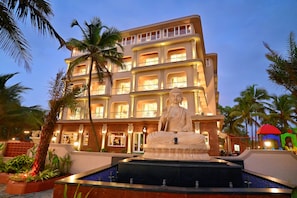 Un hotel de varios pisos con una estatua en el patio.