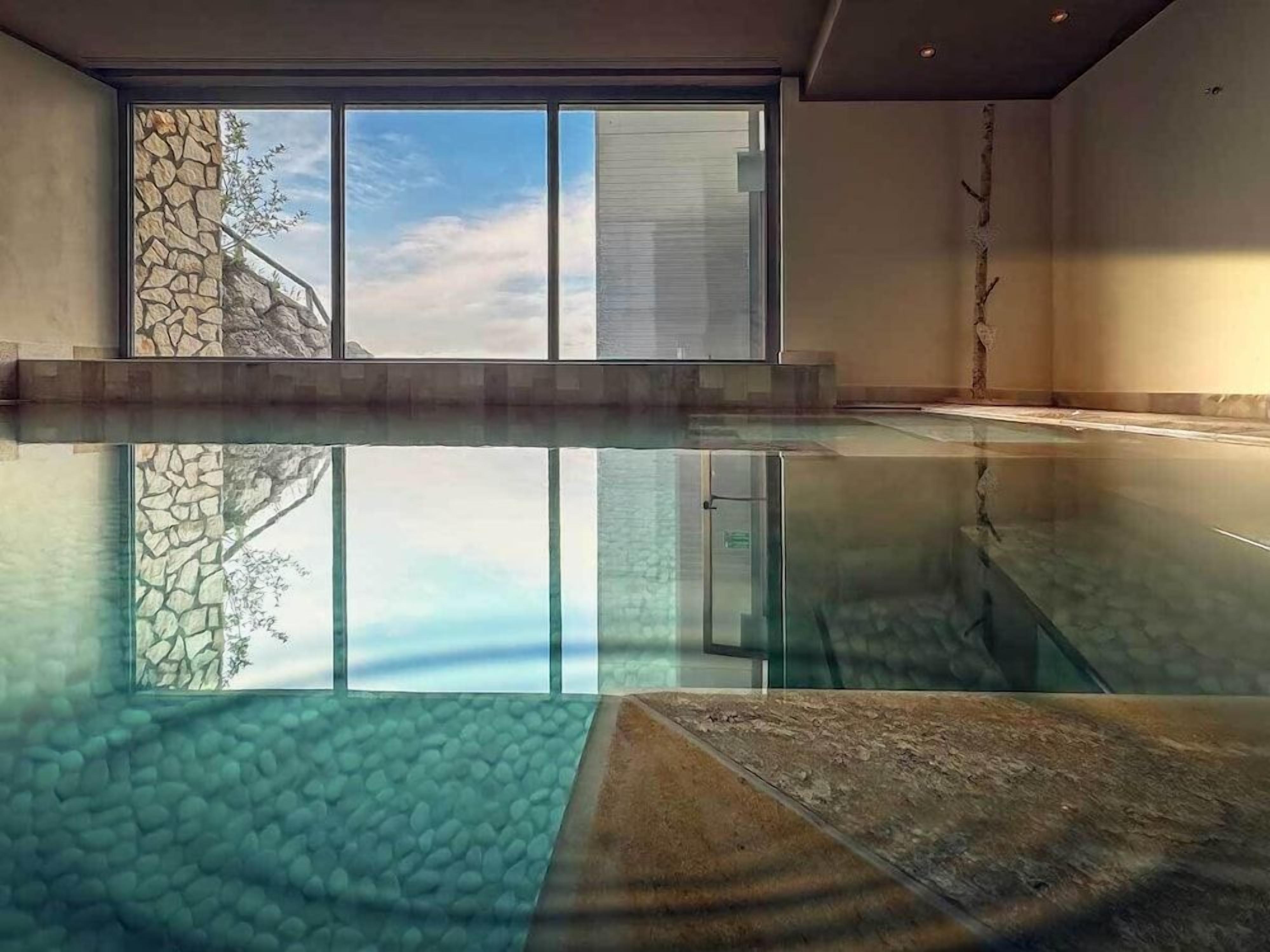 An indoor swimming pool with a clear view of the sky through large windows.
