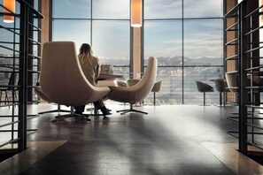 En rummelig stue med stort vindue og udsigt til bjerge, moderne stole og et minimalistisk design.