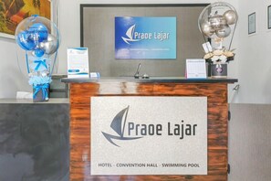 A hotel reception desk with a sign indicating the name 'Praoe Lajar' and amenities including a convention hall and swimming pool. - Urbanview Hotel Praoe Lajar Tegal (Tegal)
