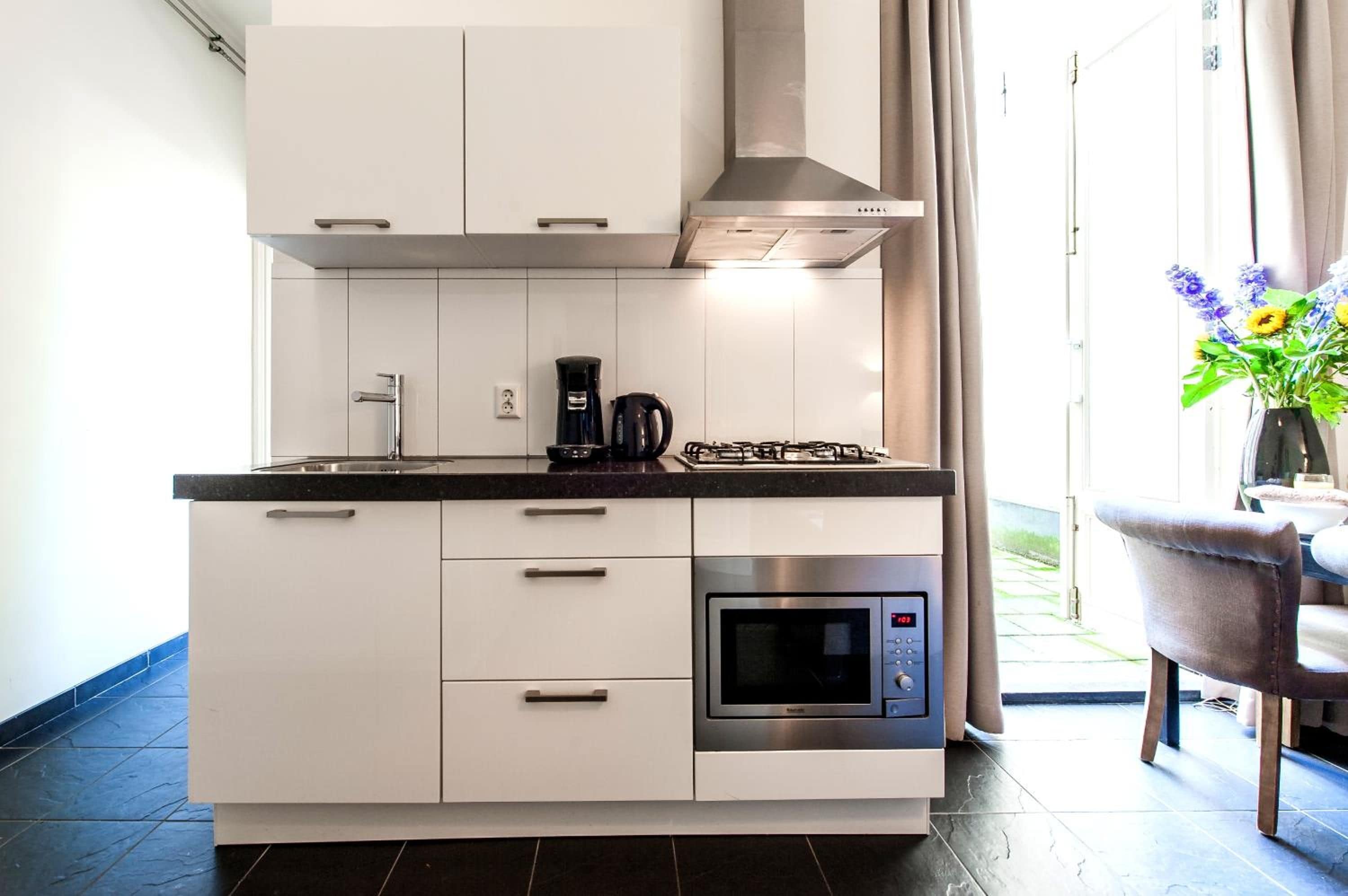 A modern kitchen with white cabinets, a built-in microwave, and a gas stove.