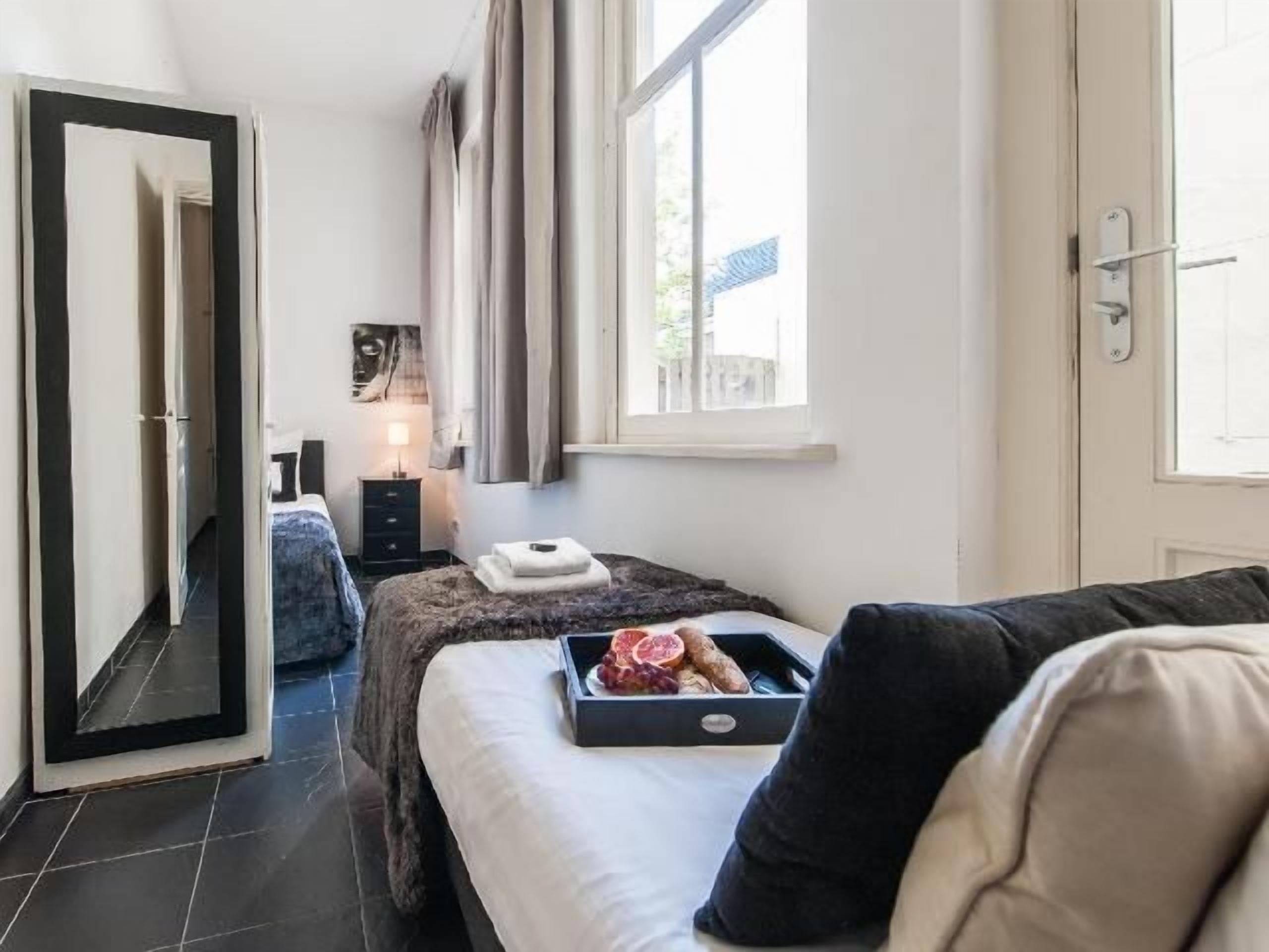 A bedroom with a bed, a dresser, a nightstand, a window, and a door.