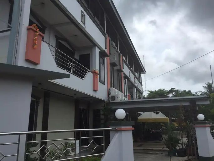 A multi-story building with balconies, a covered entrance, and a clear sky.
